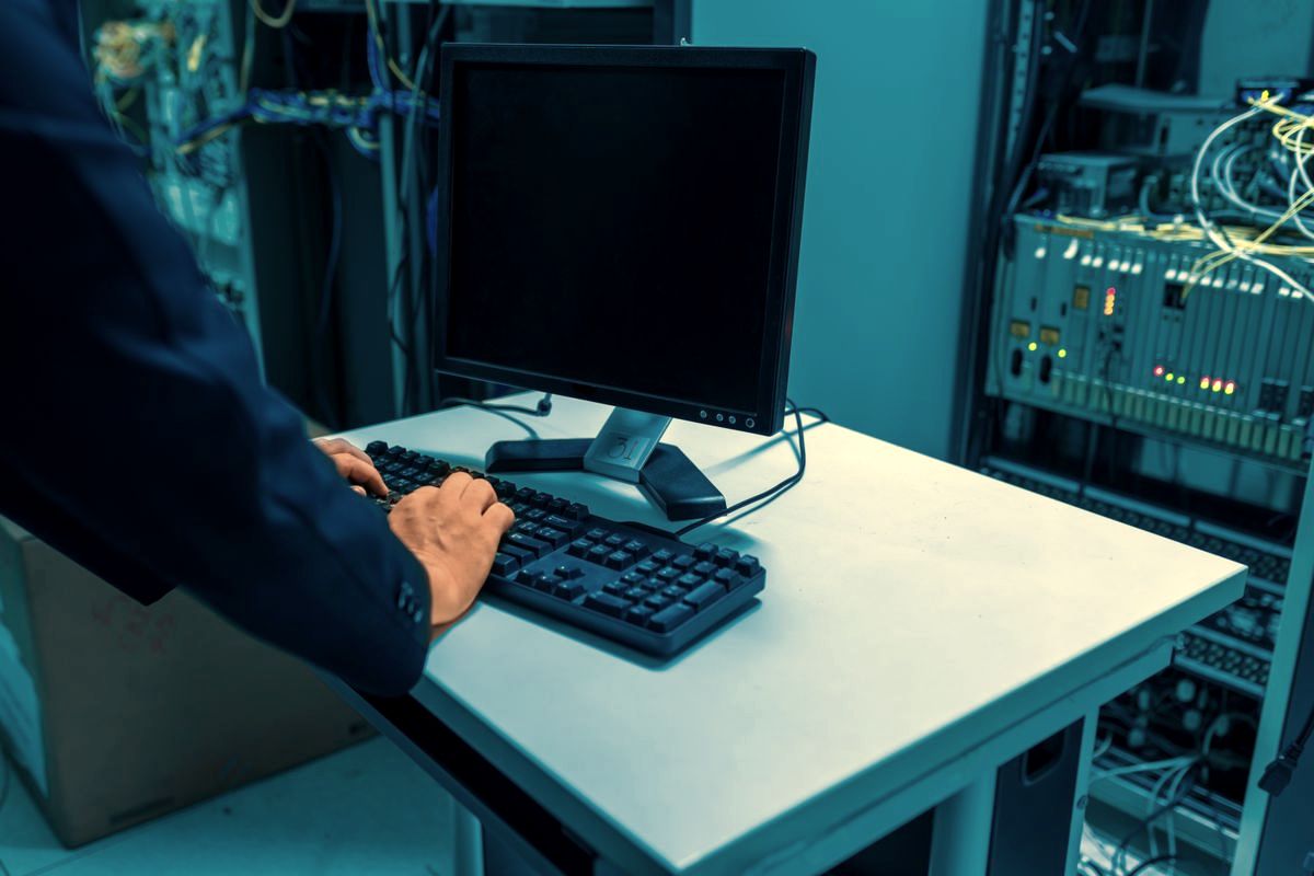 Technician working at a console beside server and network racks in a data center room